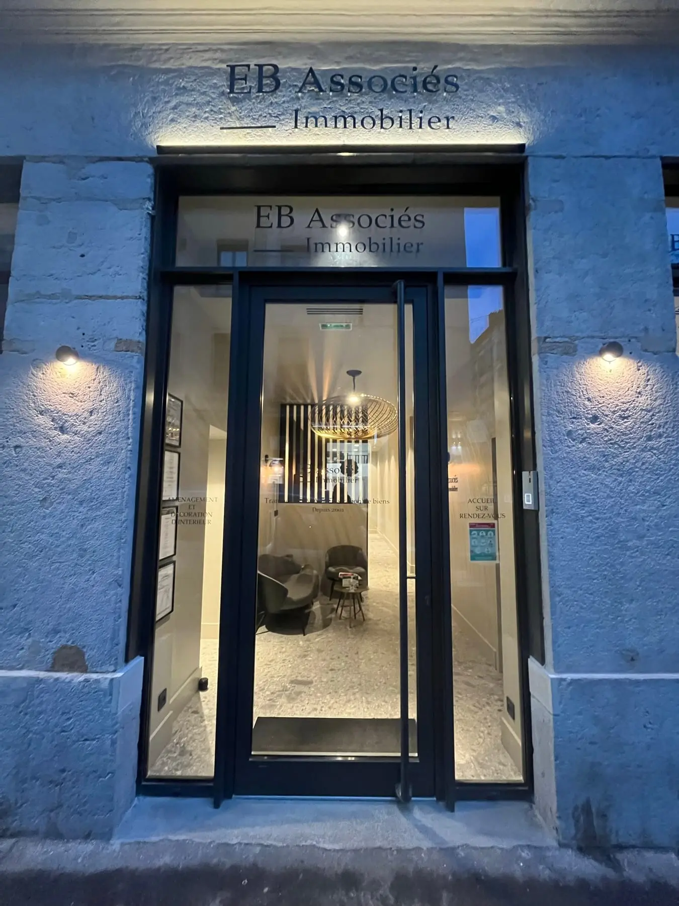 Entrée de l'agence EB Associés éclairée en soirée